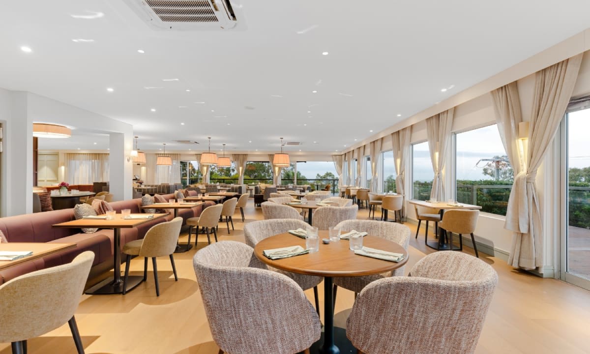 Dining room of the Glasshouse Restaurant at Peppers Clear Mountain, round tables and bay windows onto the valley