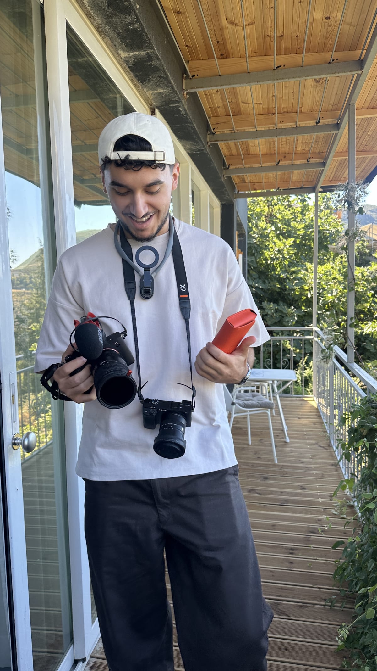 Théo Escalante, photographe, deux appareils en main sur une terrasse