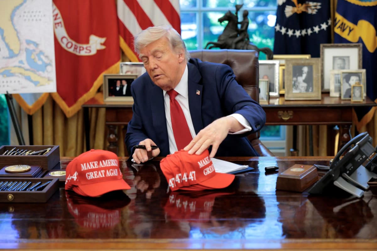 Donald Trump ajustând șepci cu mesajul MAGA în Biroul Oval