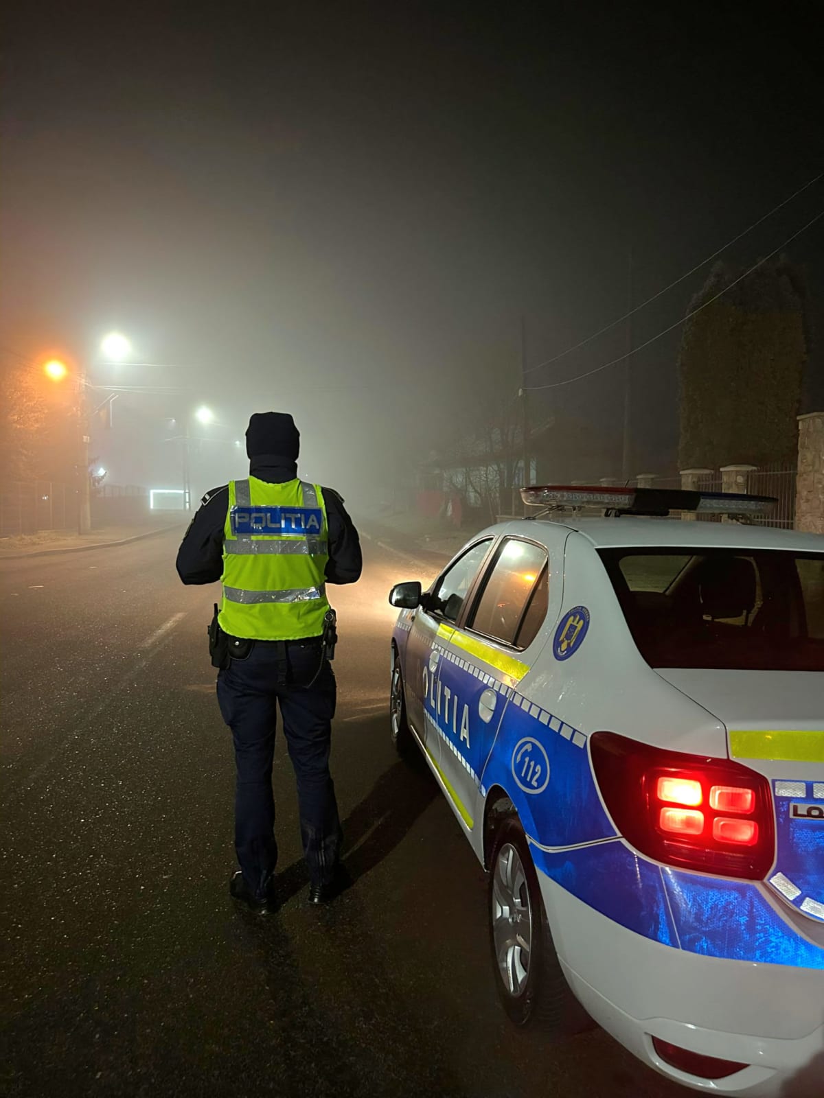 Polițist român în uniformă la o mașină de poliție