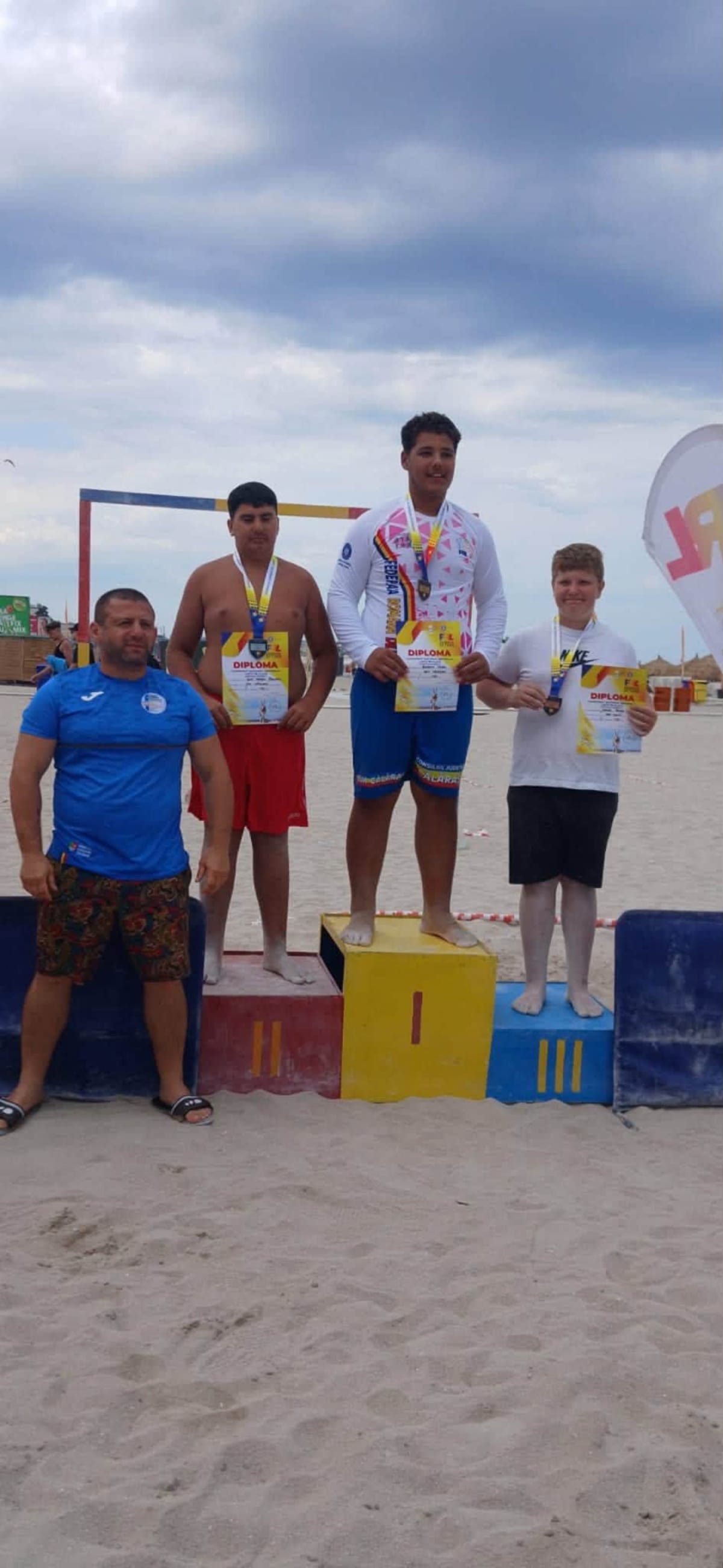 Sportiv de lupte pe plajă cu medalia de bronz în mână Sportiv de lupte pe plajă cu medalia de bronz în mână
