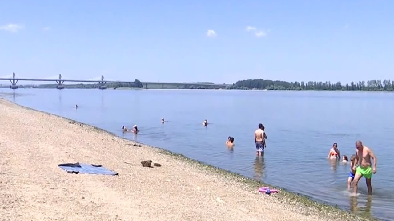 Plajă pe malul Dunării cu șezlonguri și oameni relaxându-se