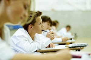 Elevi susținând examenul național în sala de clasă