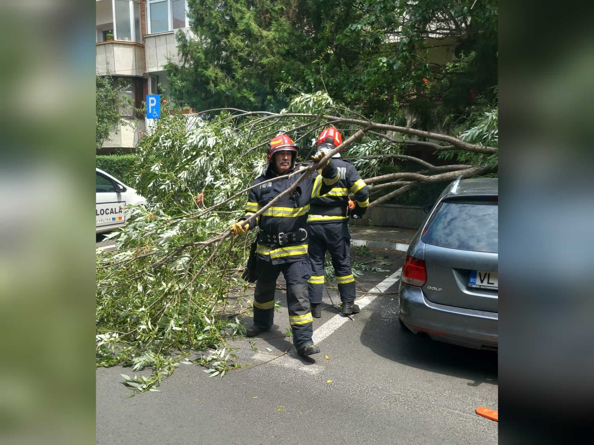 Pompieri în acțiune degajând o creangă căzută peste un autoturism