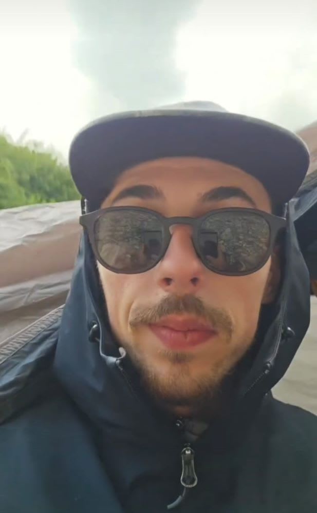 Tânăr pedalează pe bicicletă în peisaj european, cu Barcelona în fundal