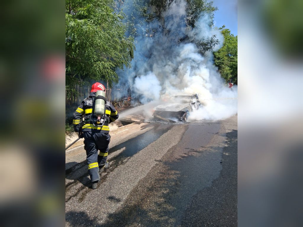 Pompieri români stingând incendiu la mașină în Vâlcea