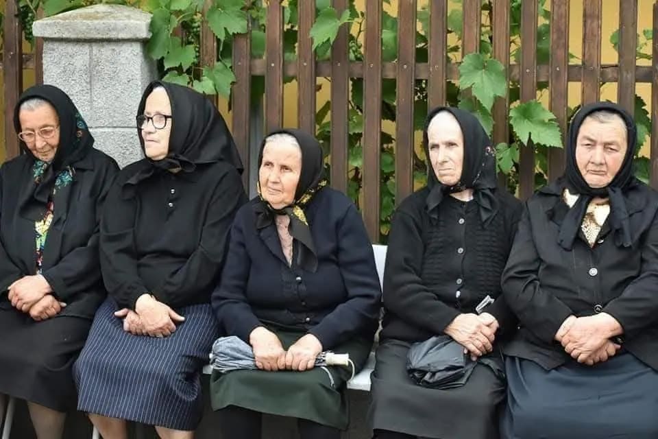 Fotografie cu cinci văduve din satul de lângă Onești în fața troiței
