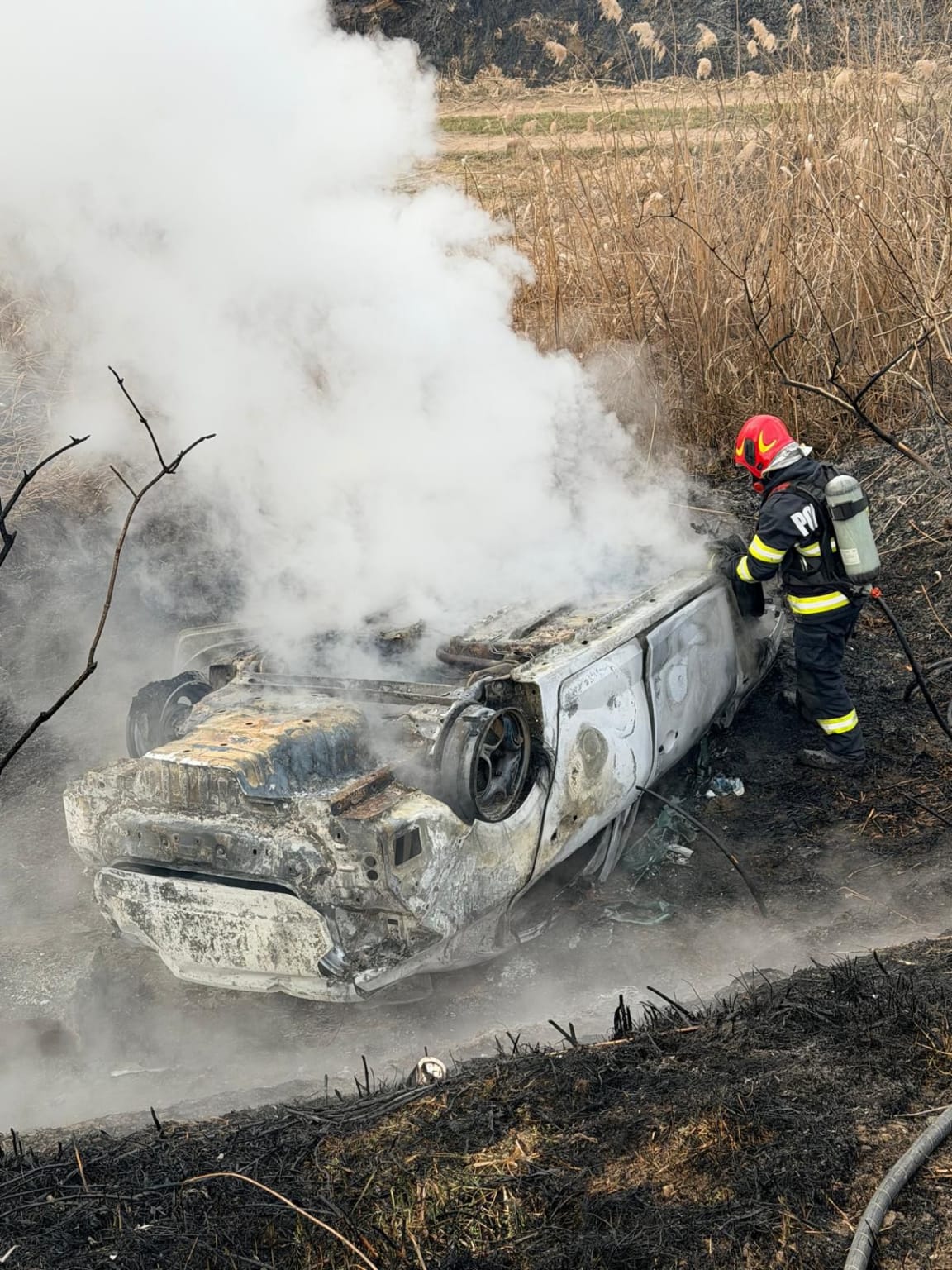 Pompieri stingând incendiu la mașină în județul Mureș
