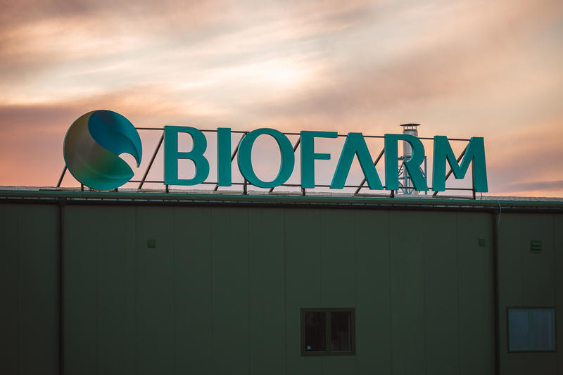 Echipă farmaceutică în fabrică, logo Biofarm și Polpharma