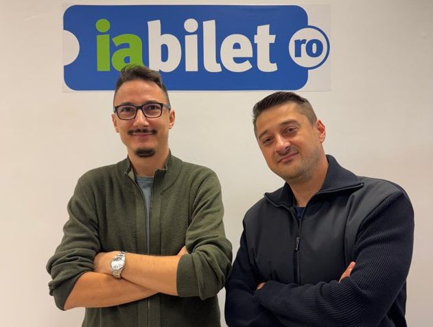 Echipă de specialiști în tehnologie și ticketing în fața unui ecran digital