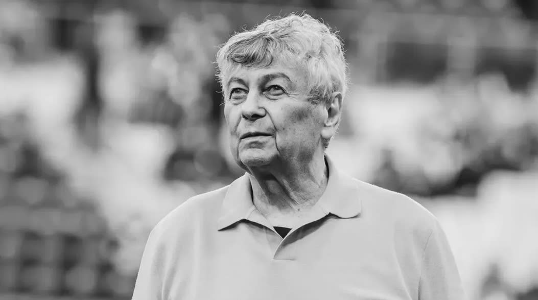 Mircea Lucescu în timpul unei conferințe de presă, în fața unei table cu grafice financiare
