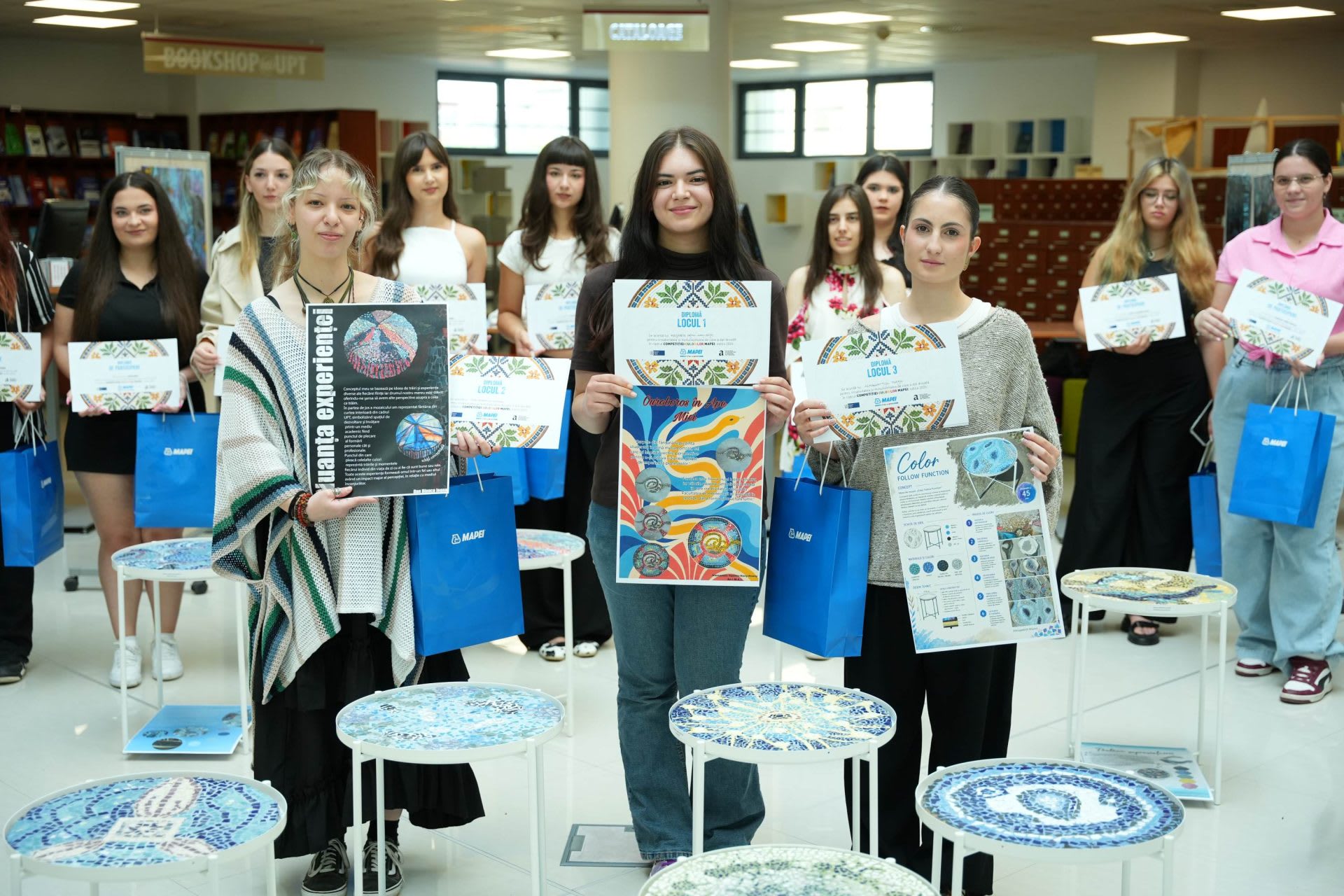 Studenți arhitecți prezentând lucrări de mozaic în expoziție