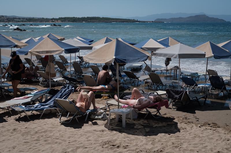 Plajă din Grecia plină de șezlonguri, turiști pe litoral