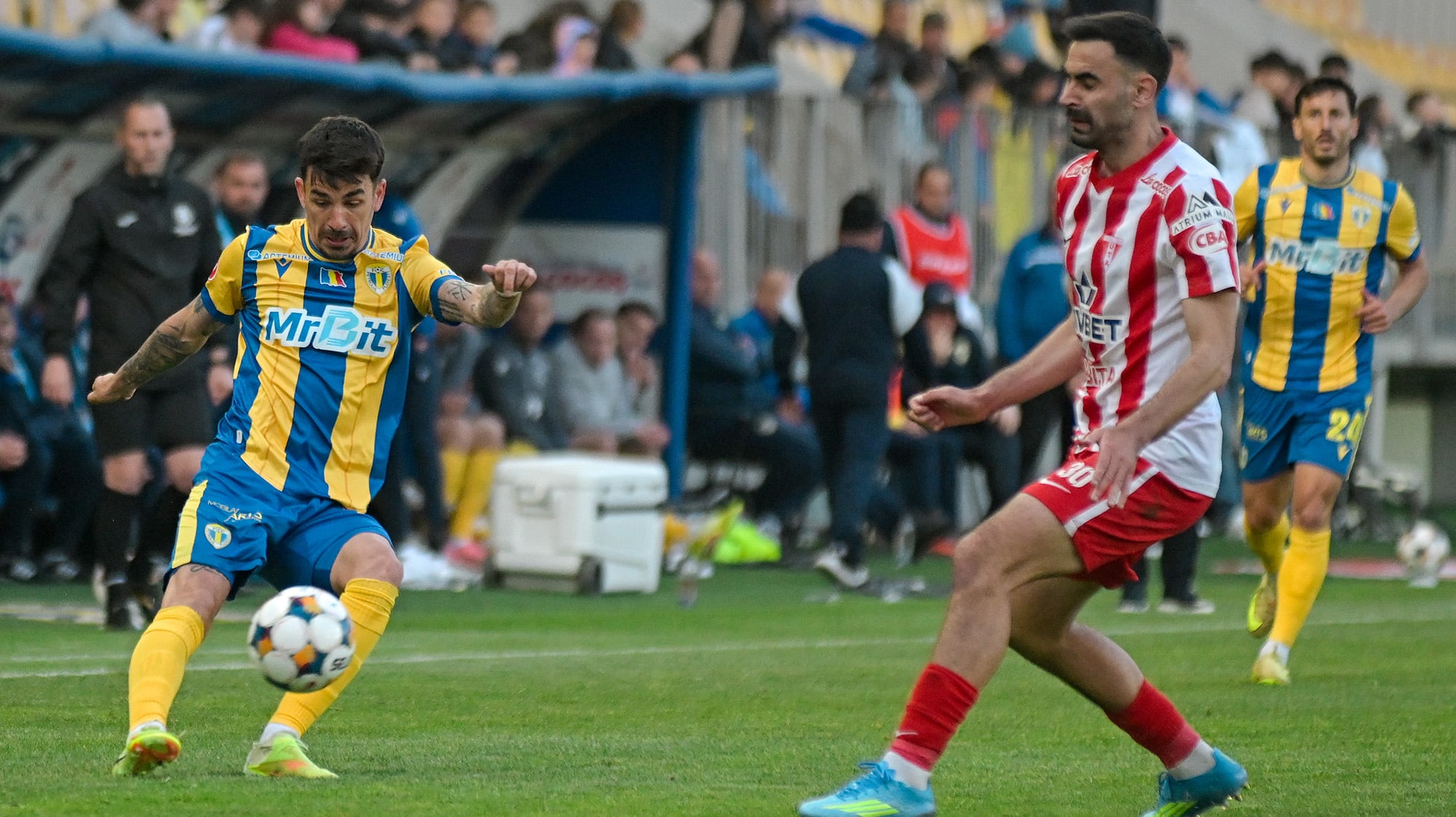 Jucători de fotbal în acțiune pe terenul din Mioveni, stadionul Stadionul Orășenesc Jucători de fotbal în acțiune pe terenul din Mioveni, stadionul Stadionul Orășenesc