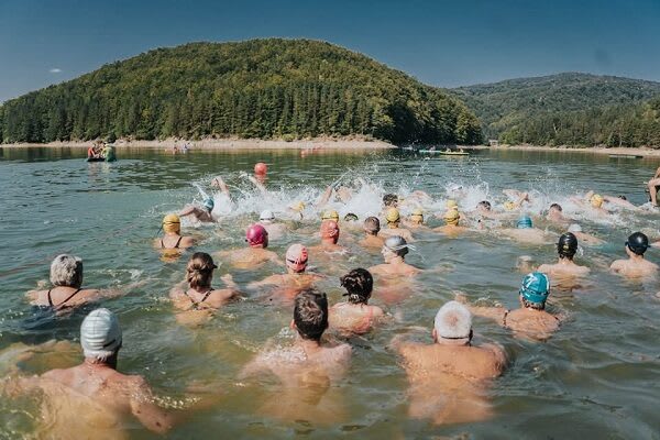 Participanți înotând în Lacul Gozna la Traversarea Văliug 2026