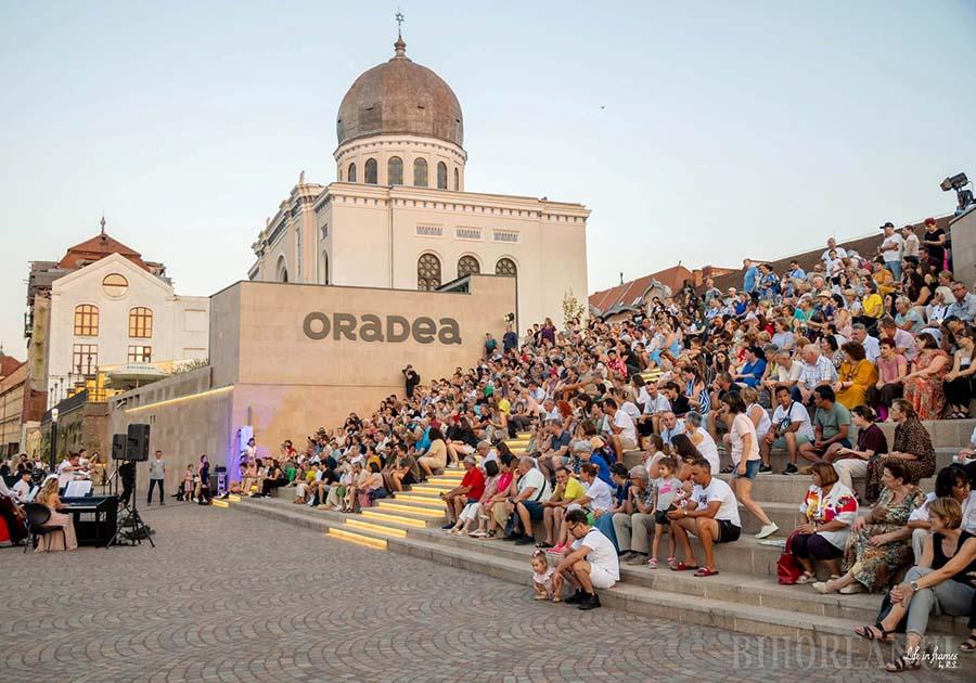 Spectacol muzical în aer liber, scena Filarmonicii din Oradea, oameni în picioare, cer senin