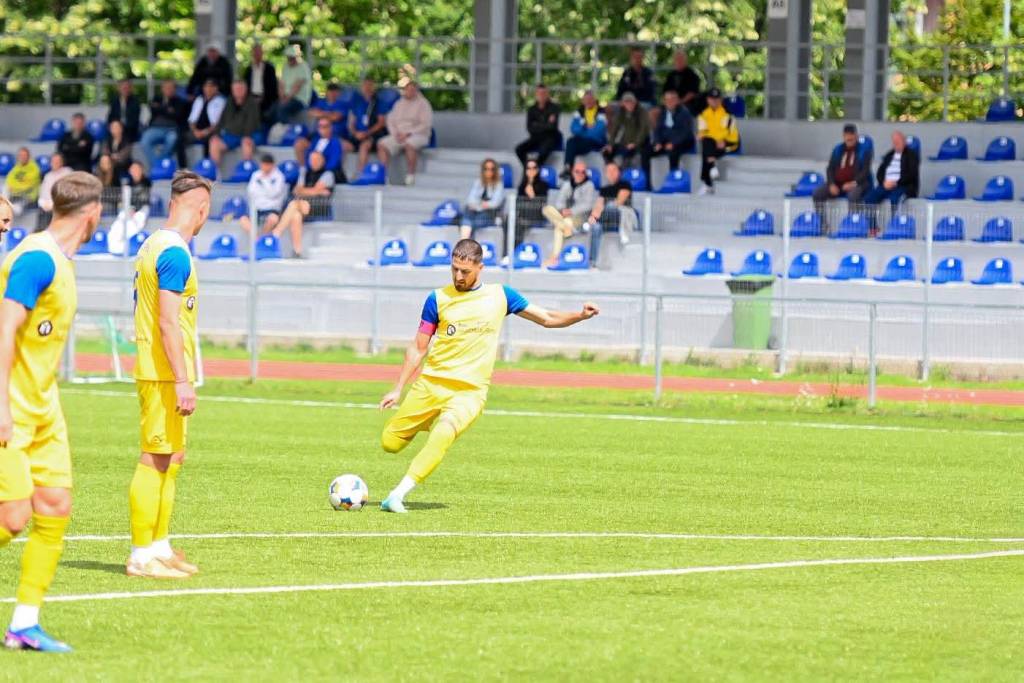 Jucători de fotbal în acțiune pe terenul stadionului Carpați din Brașov