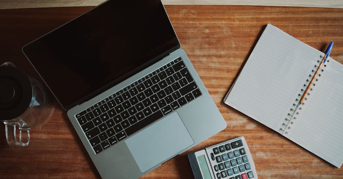 Persoană verificând documente financiare și calculator online