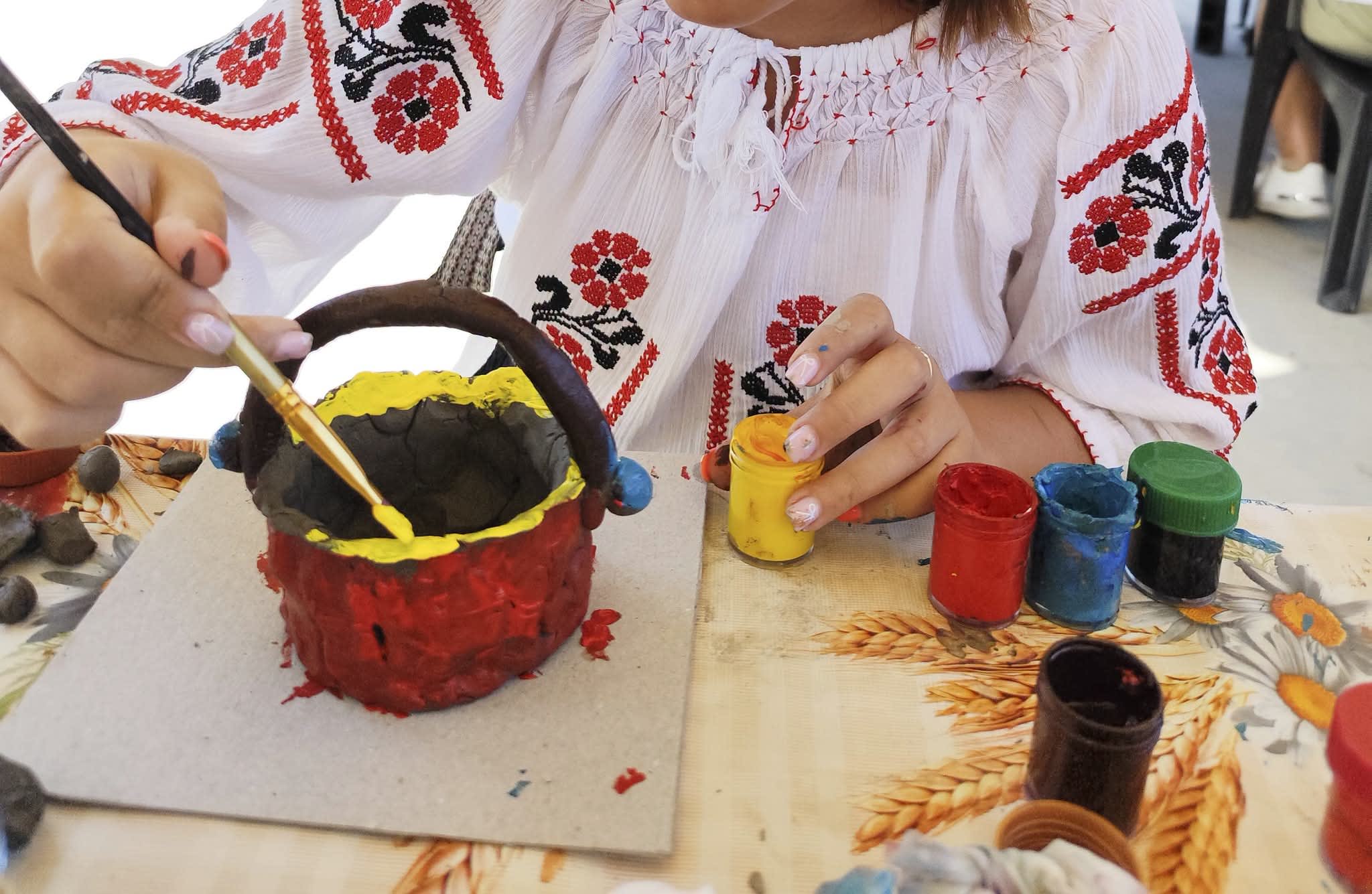 Participanți modelând lut la atelier de ceramică tradițională în muzeu Participanți modelând lut la atelier de ceramică tradițională în muzeu