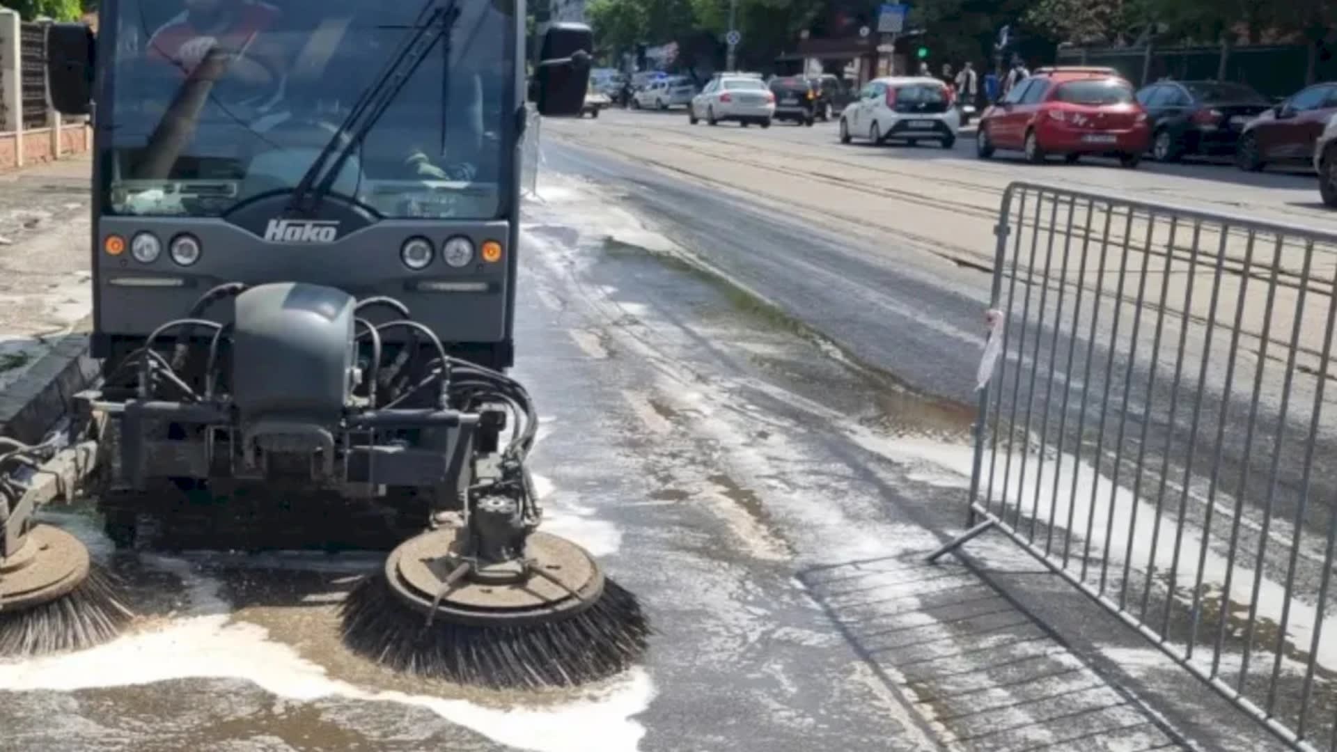 Echipă de muncitori spălând strada cu mașini speciale în București Echipă de muncitori spălând strada cu mașini speciale în București
