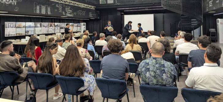 Absolvenți în halat academic primind diplomele în sala ARChA