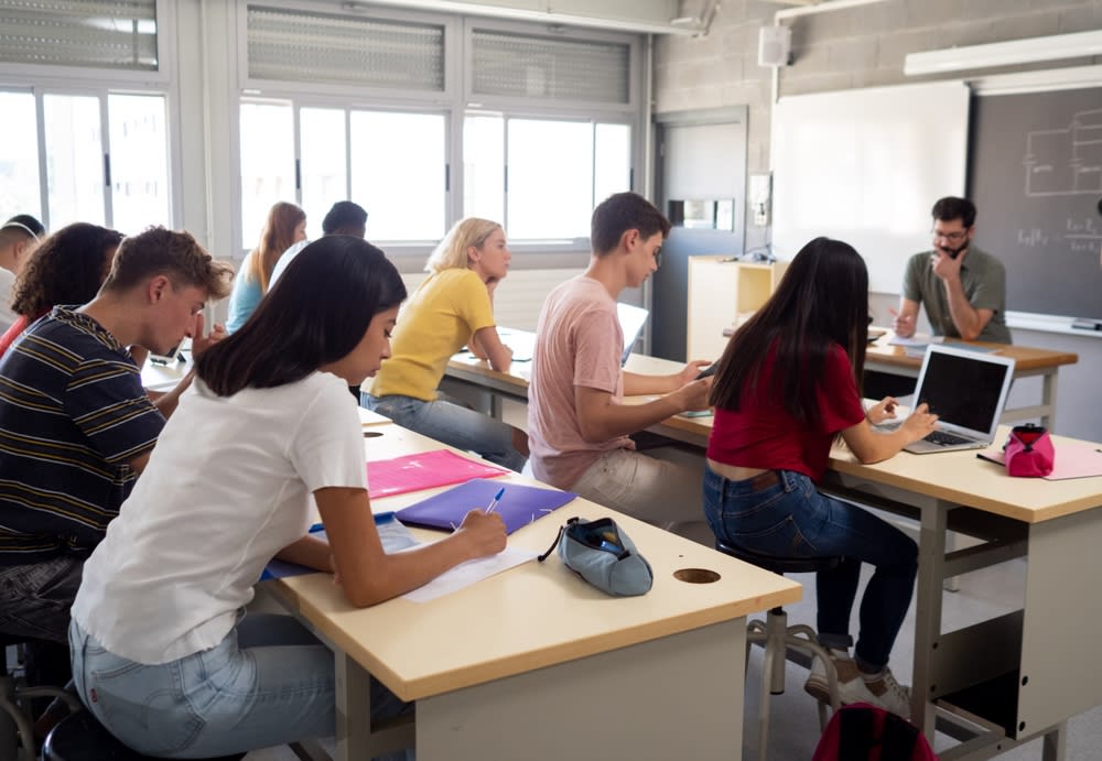 Elevi în clasă cu manuale și tablete, învățare modernă Elevi în clasă cu manuale și tablete, învățare modernă