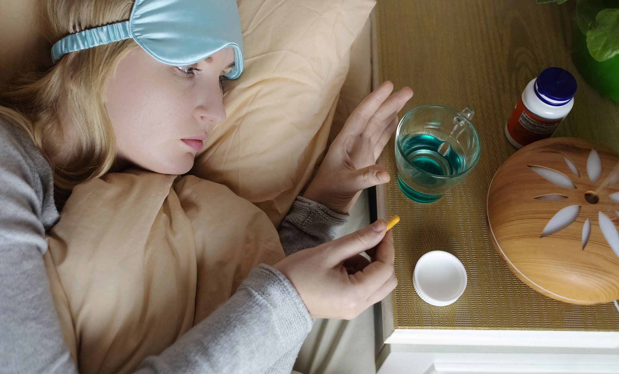 Suplimente de melatonină și magneziu pe o masă, cu un pahar de apă Suplimente de melatonină și magneziu pe o masă, cu un pahar de apă