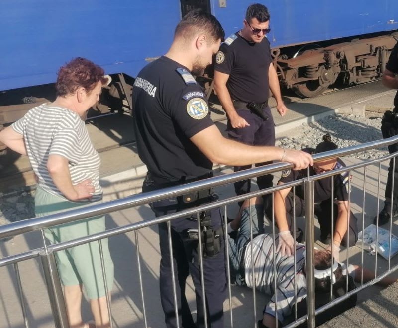 Jandarmi acordând primul ajutor unui bărbat rănit pe peronul gării din Costinești