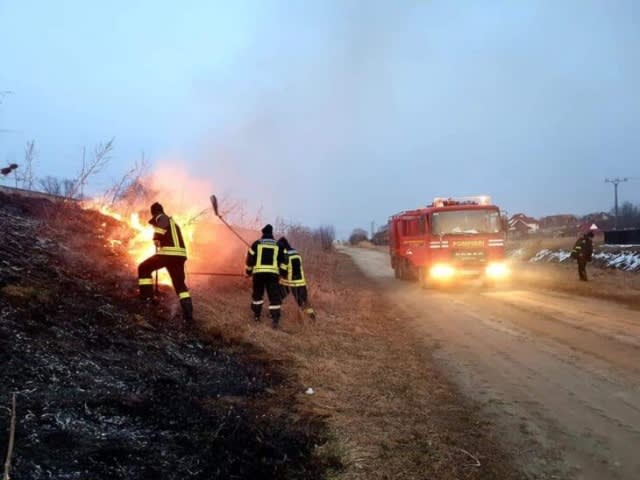 Pompieri stingând incendiu de vegetație uscată în România Pompieri stingând incendiu de vegetație uscată în România