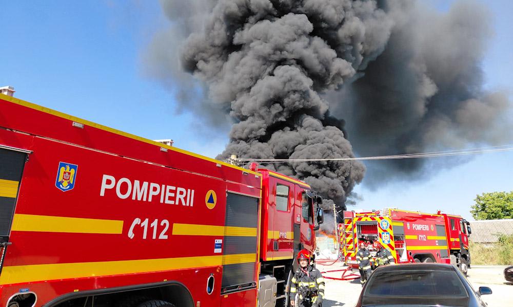 Pompieri români stingând incendiu la hală de deșeuri în Băicoi Pompieri români stingând incendiu la hală de deșeuri în Băicoi