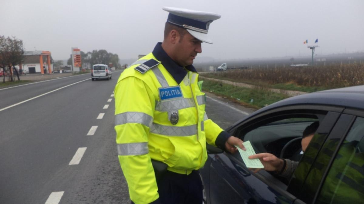 Polițist rutier cu semn de oprire în trafic, mașini în fundal Polițist rutier cu semn de oprire în trafic, mașini în fundal