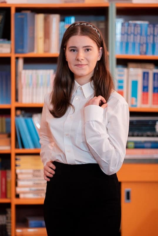 Xenia Mariciuc în uniformă de elevă, zâmbind în fața liceului Xenia Mariciuc în uniformă de elevă, zâmbind în fața liceului