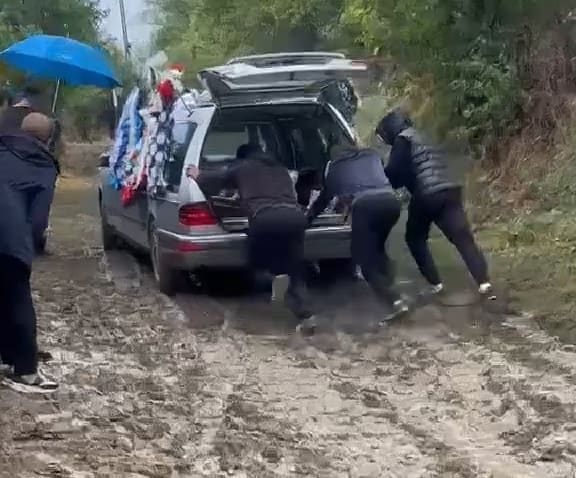 mașină mortuară împinsă prin noroi pe uliță în Cârja mașină mortuară împinsă prin noroi pe uliță în Cârja