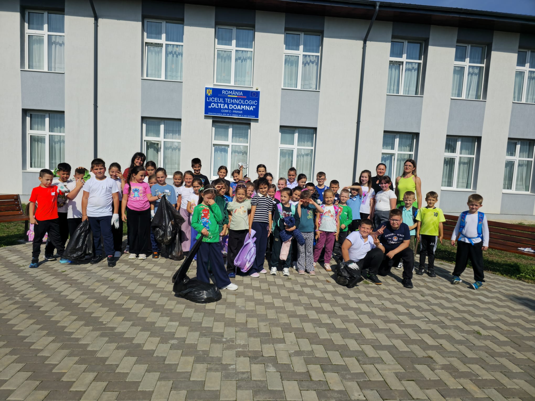 Elevi și profesori ecologizând spații verzi, saci de deșeuri și mănuși de protecție