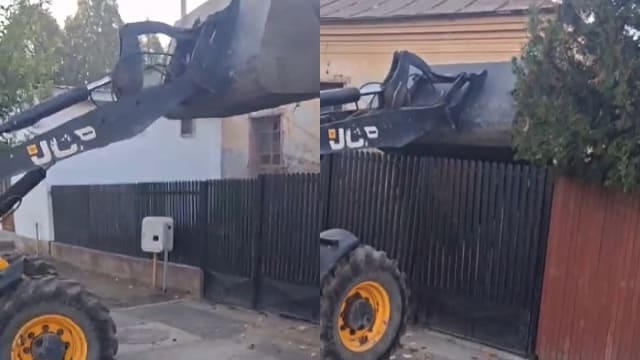 buldoexcavator răsturnând deșeuri peste poarta unei case