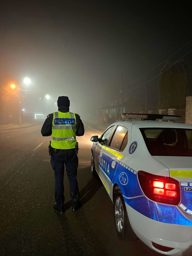 Polițist român în uniformă la o mașină de poliție
