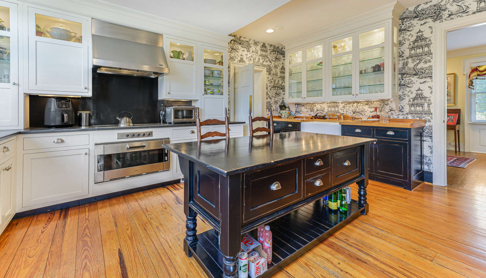 The kitchen, heart pine underfoot, black granite, a range under its hood