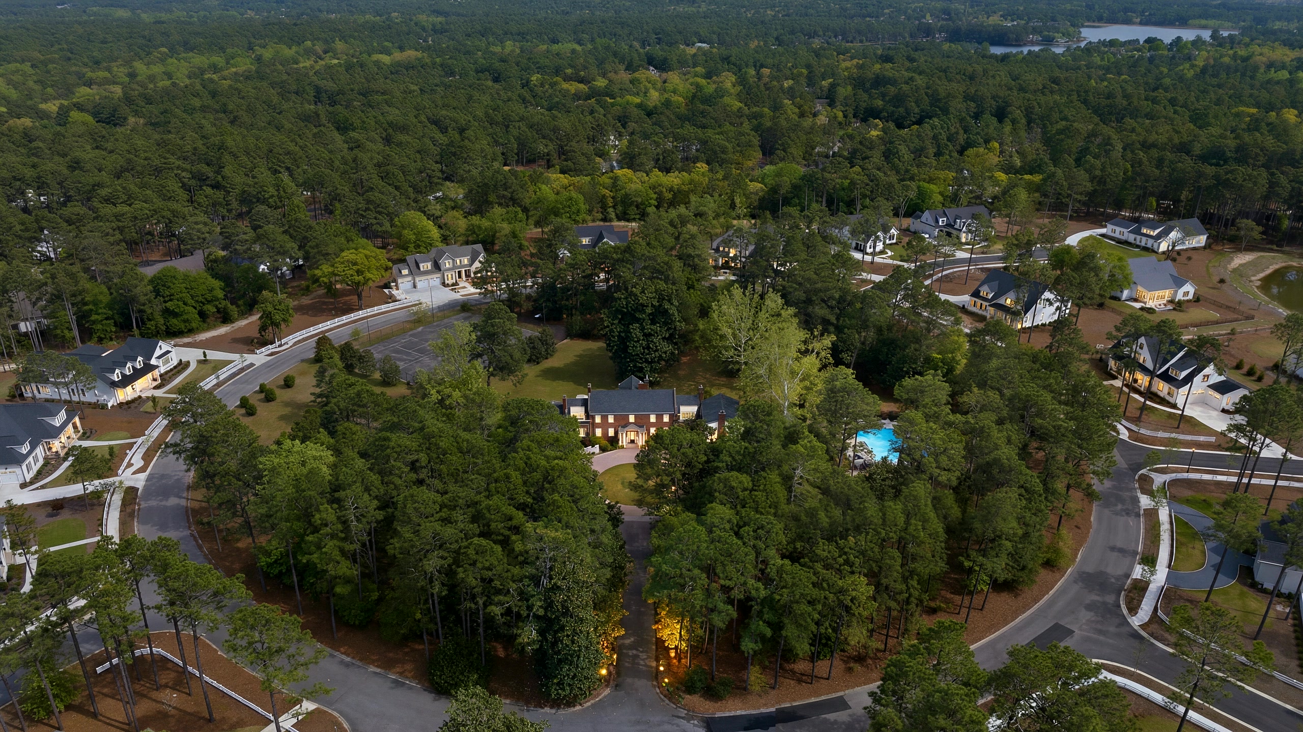 Garran Hill from above at dusk, the windows lit, alone in its own circle of trees