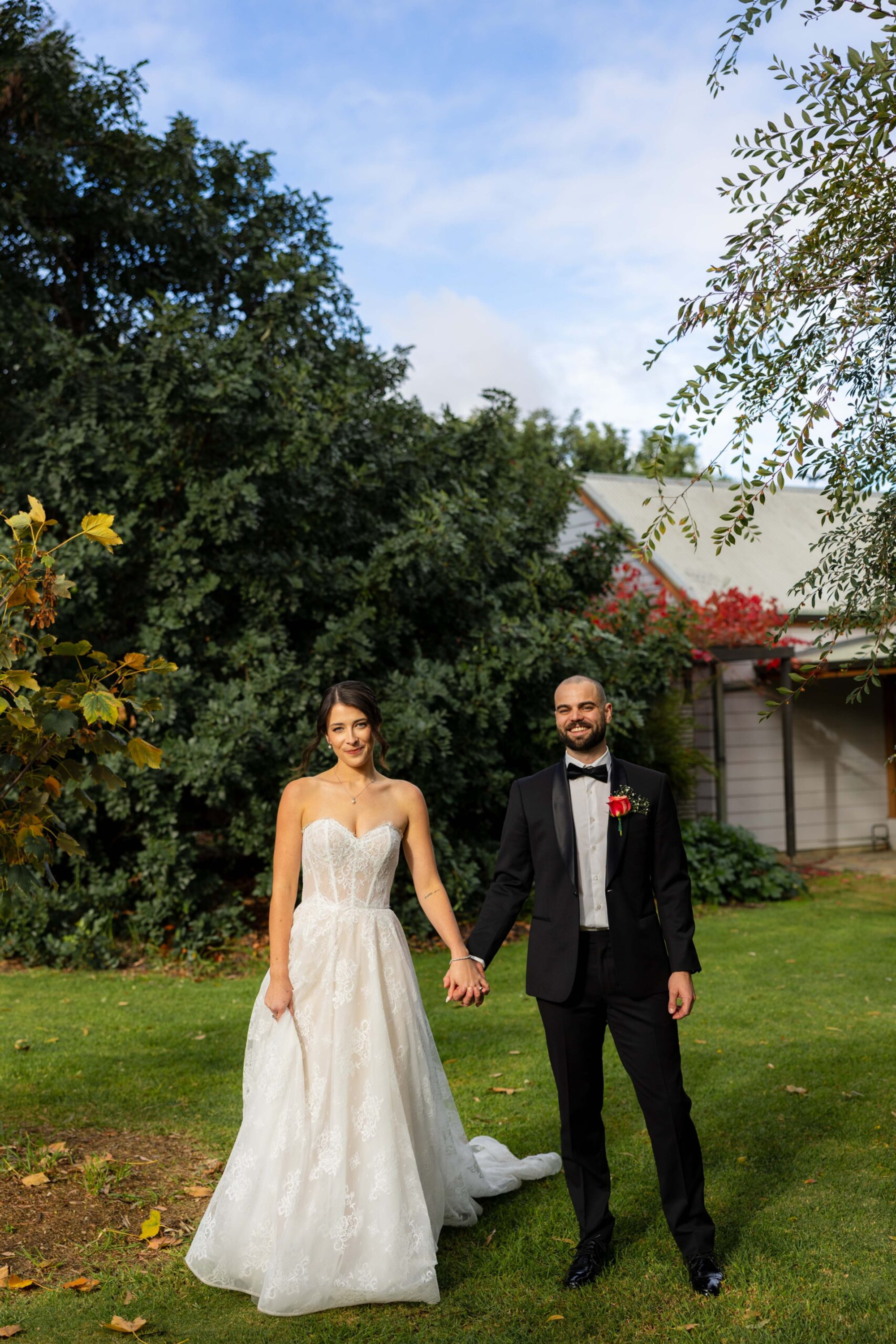 Bride and groom holding hands in a green garden outside a house on their wedding day