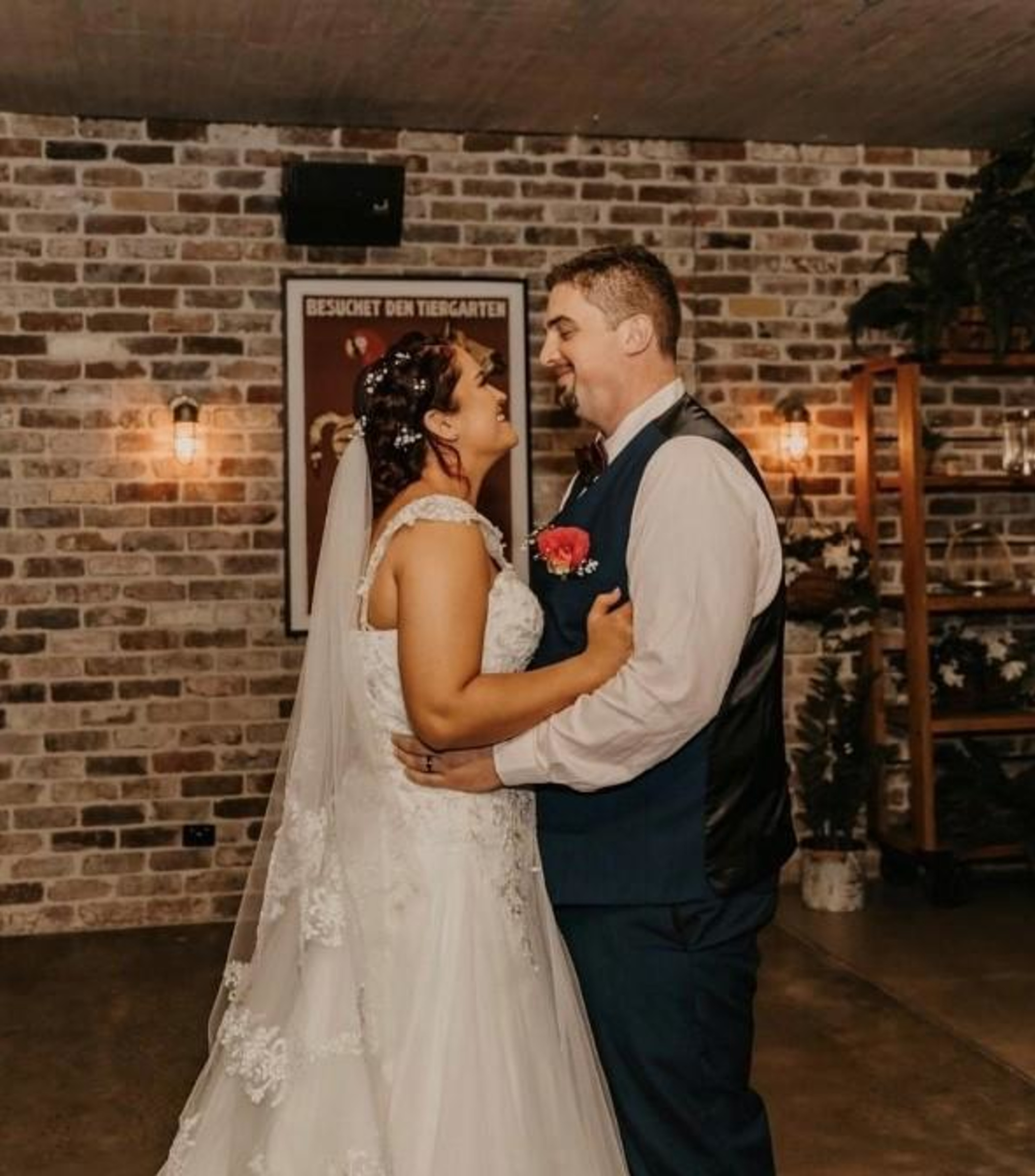 Bride and groom share a first dance in a rustic brick indoor wedding venue.
