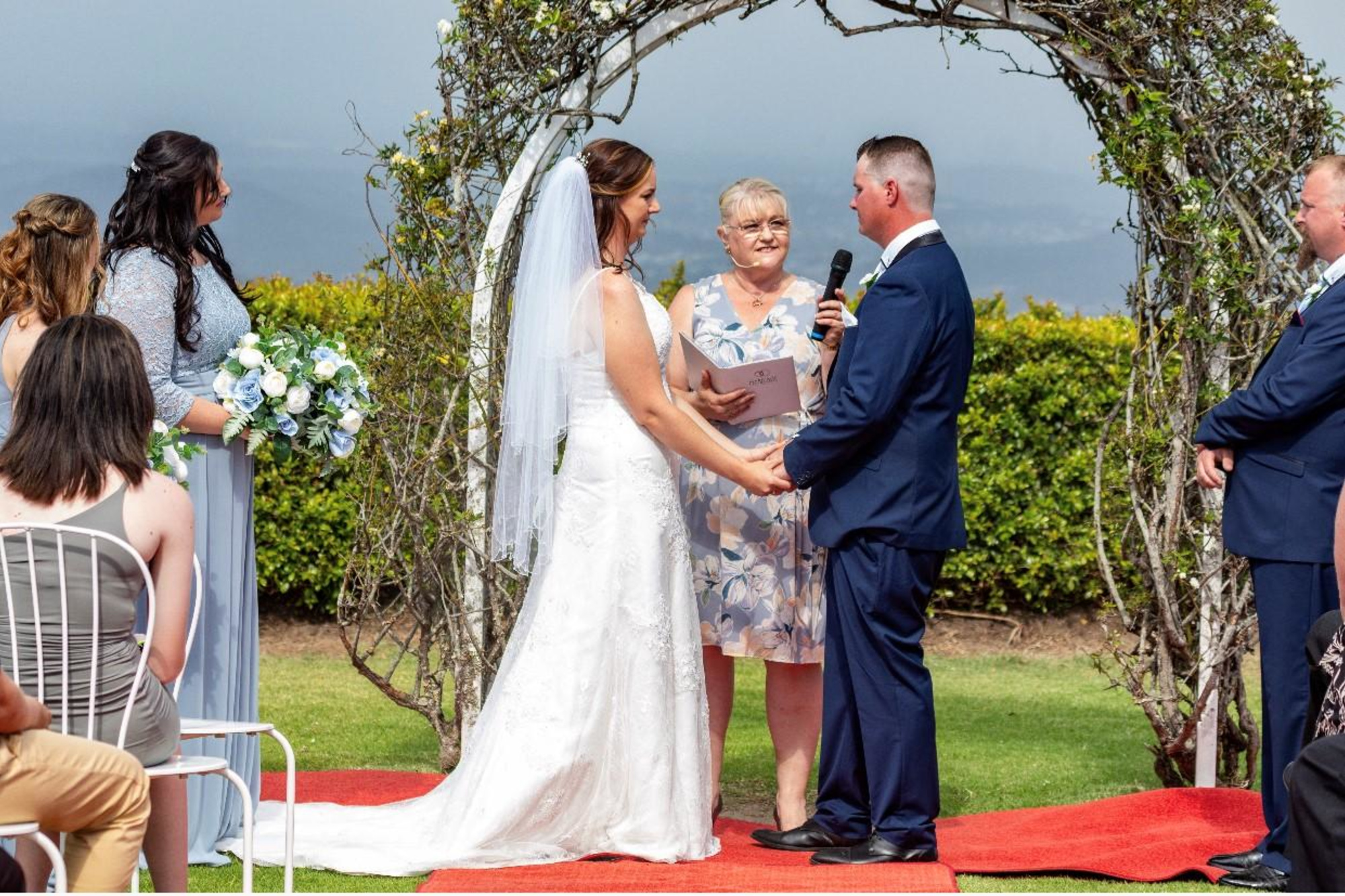 Outdoor garden wedding ceremony with a couple exchanging vows under a rustic floral arch.