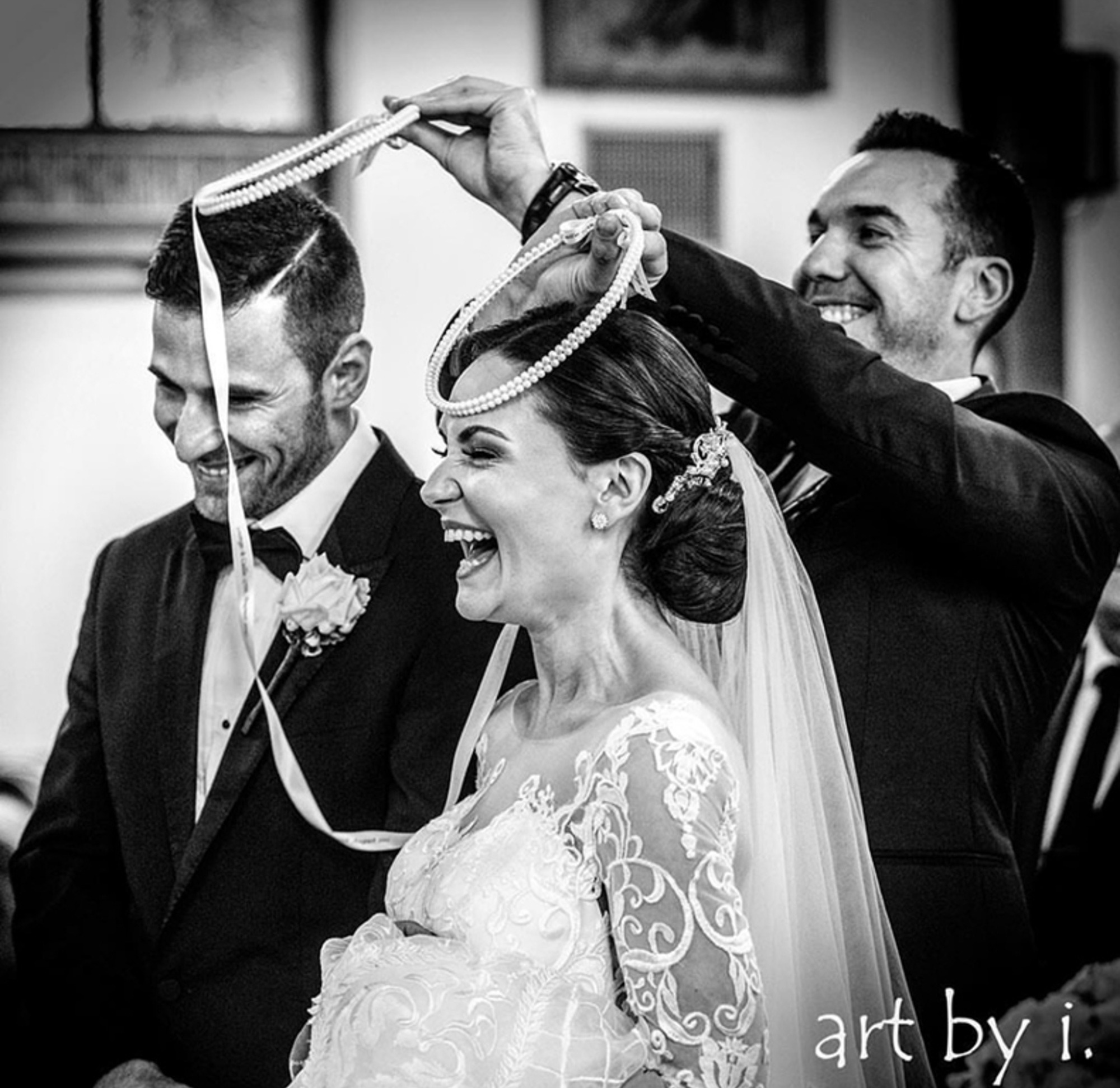 Joyful bride and groom during a church wedding ritual with crowns held above their heads.