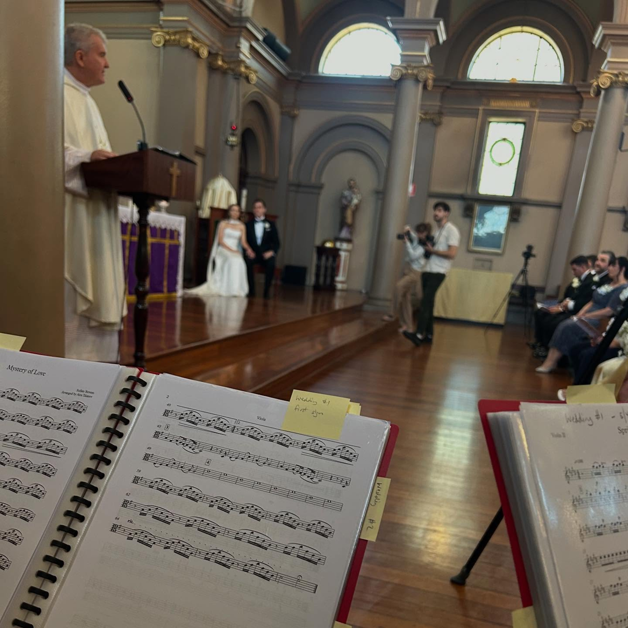 View from a musician’s stand during a church wedding ceremony with the couple at the altar.