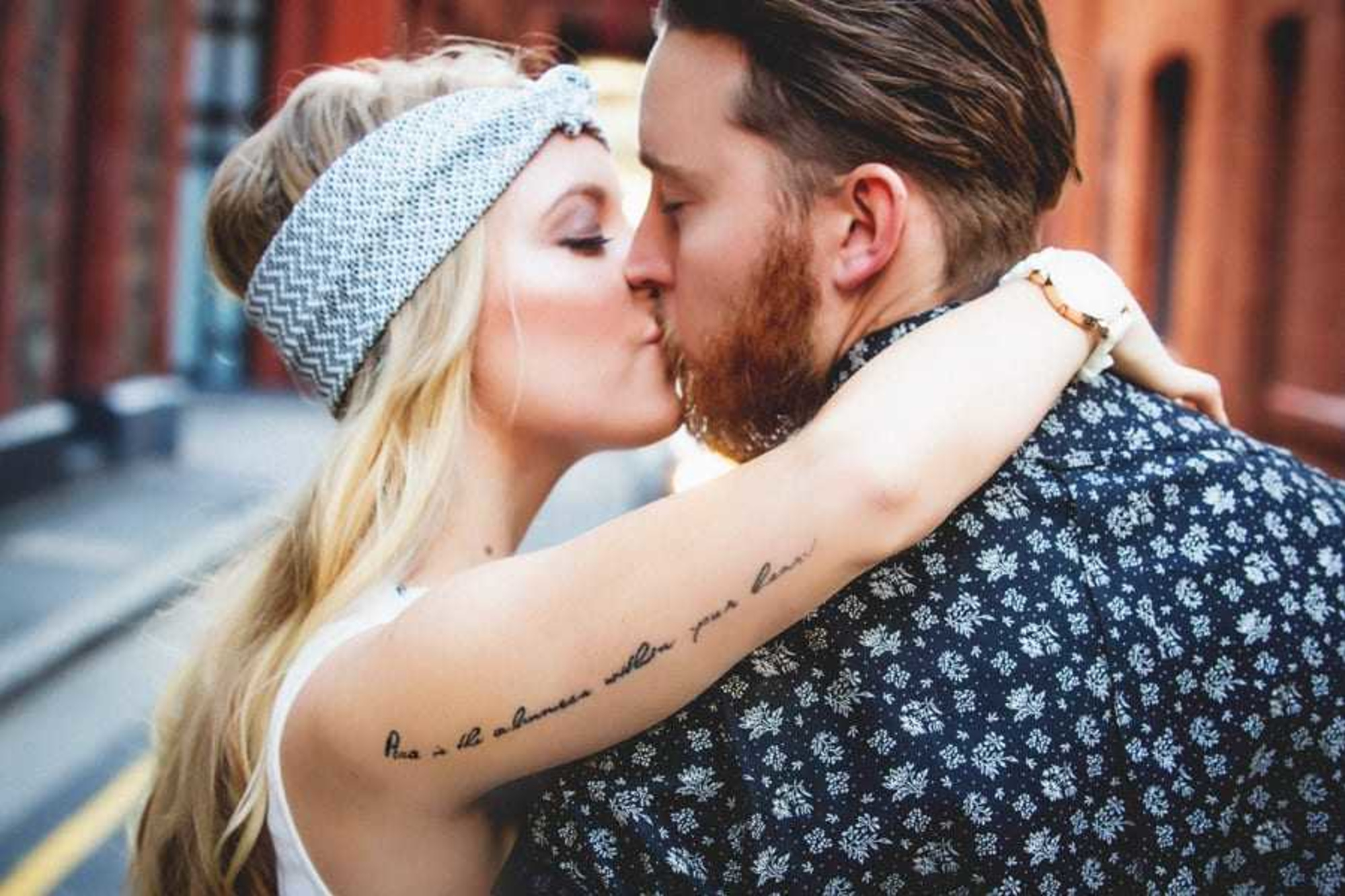 Boho couple shares a romantic kiss during an urban street photoshoot.