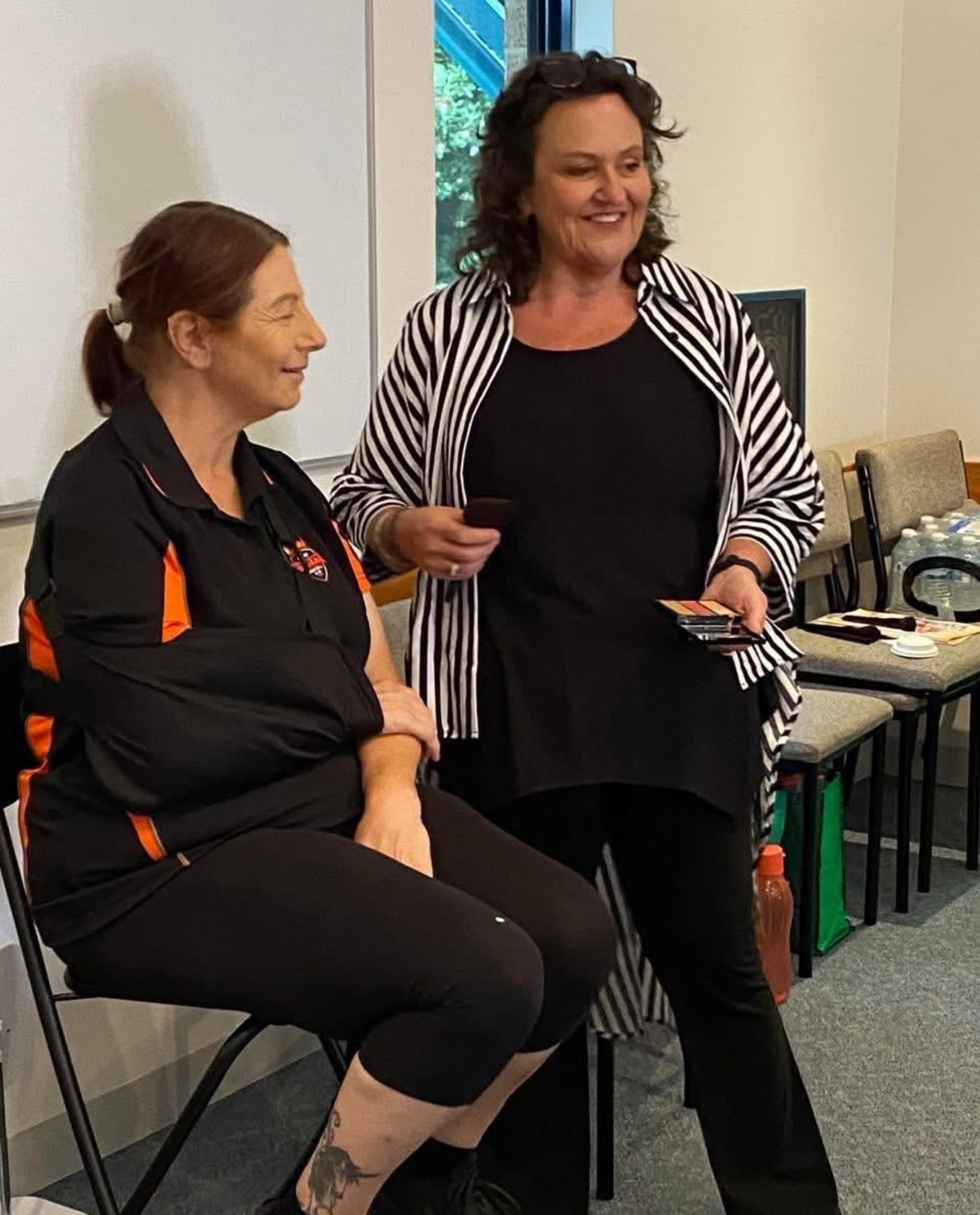 Makeup artist consulting with a seated woman during a beauty session in an indoor setting.