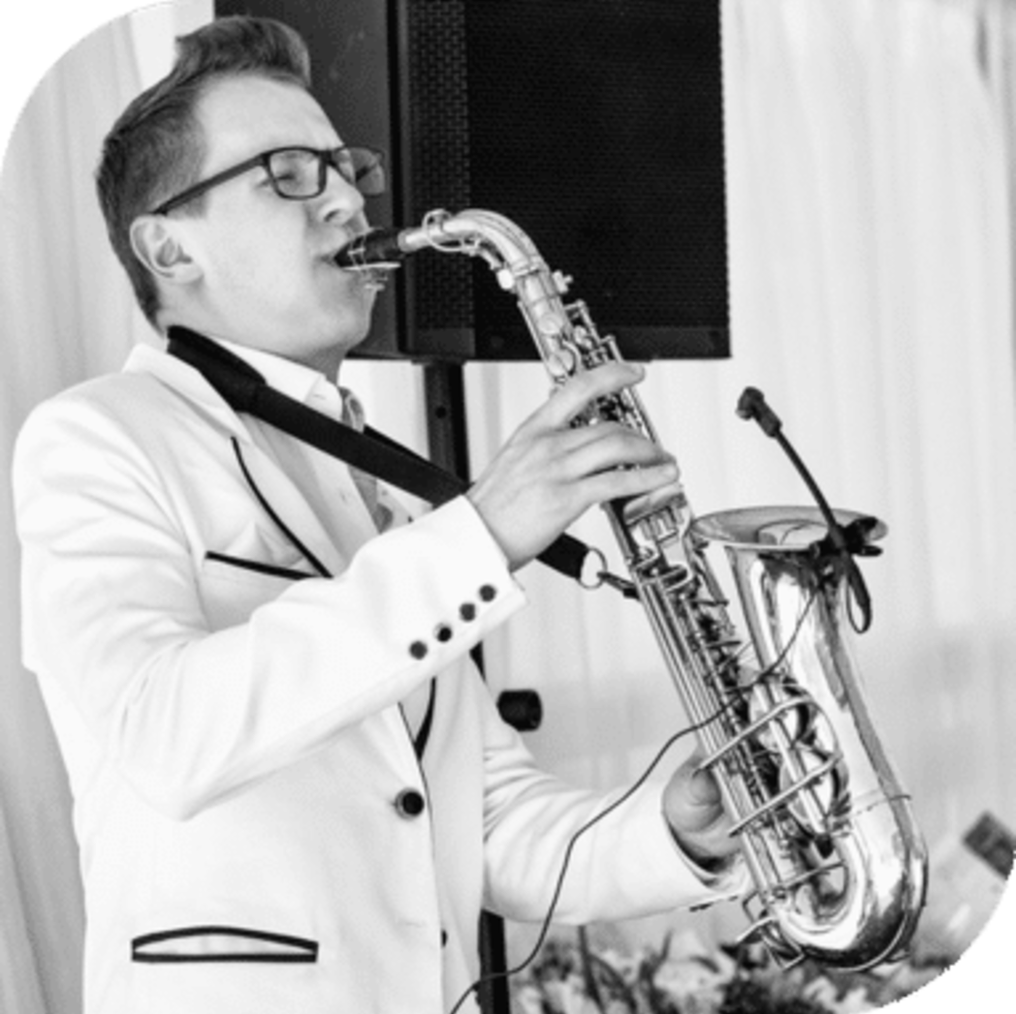A saxophonist in a white suit plays live music at a wedding reception.