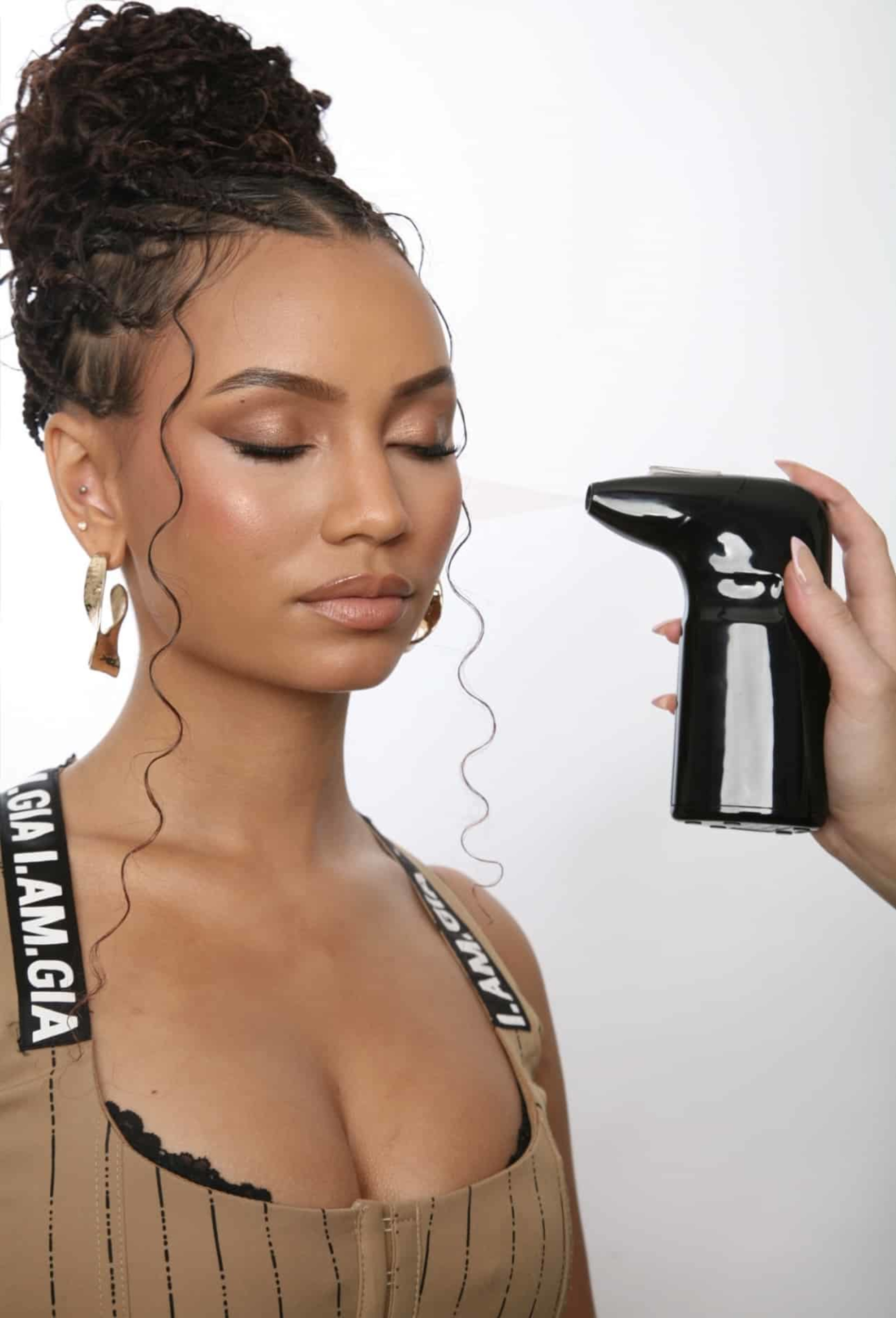 Makeup artist applies airbrush makeup to a woman with elegant bridal glam styling.