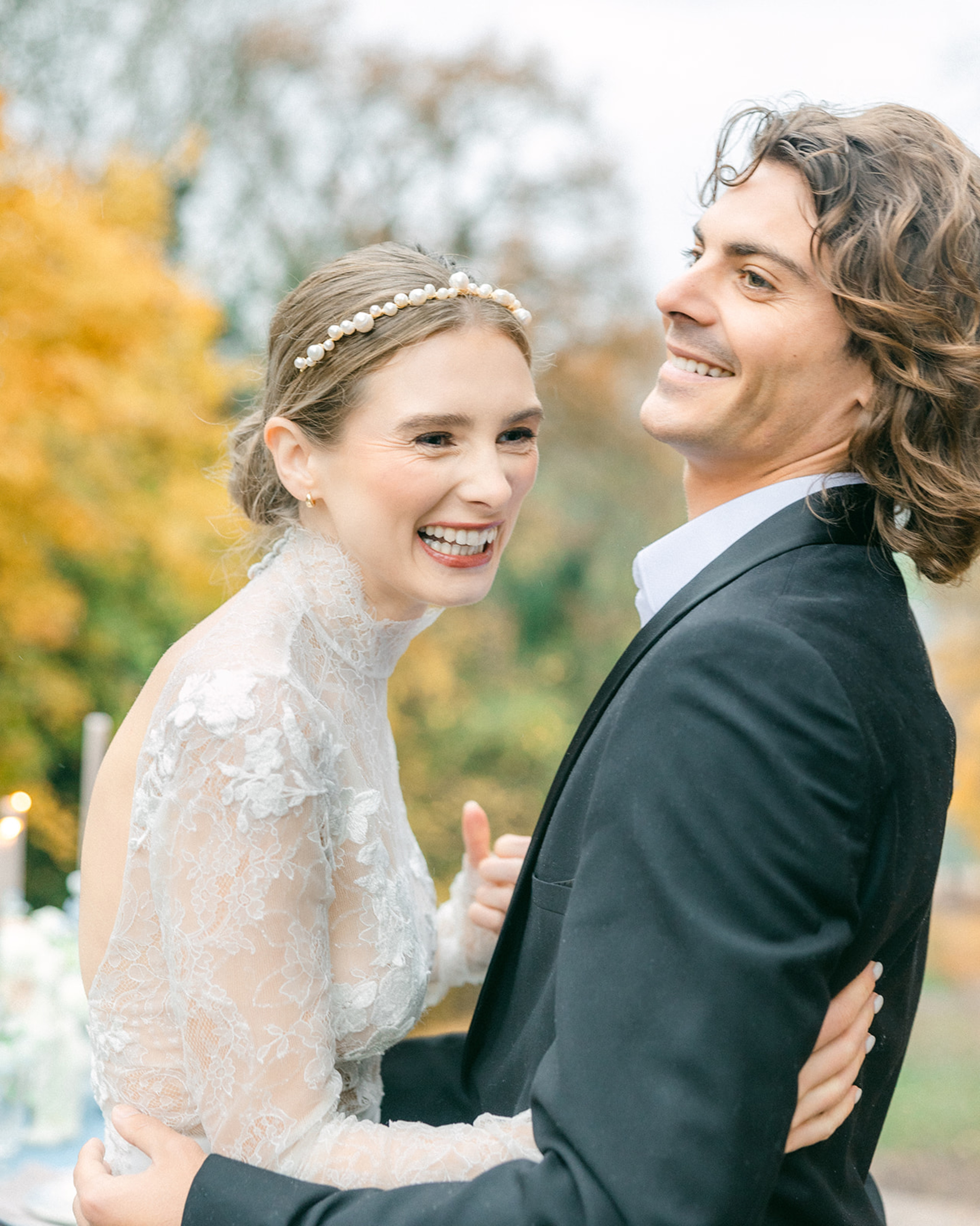 Joyful bride and groom embracing outdoors in an elegant lace dress and classic suit