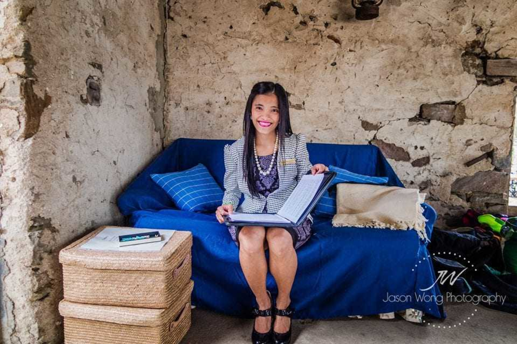 Woman sitting on a blue couch in a rustic room, smiling while showing a large wedding album.