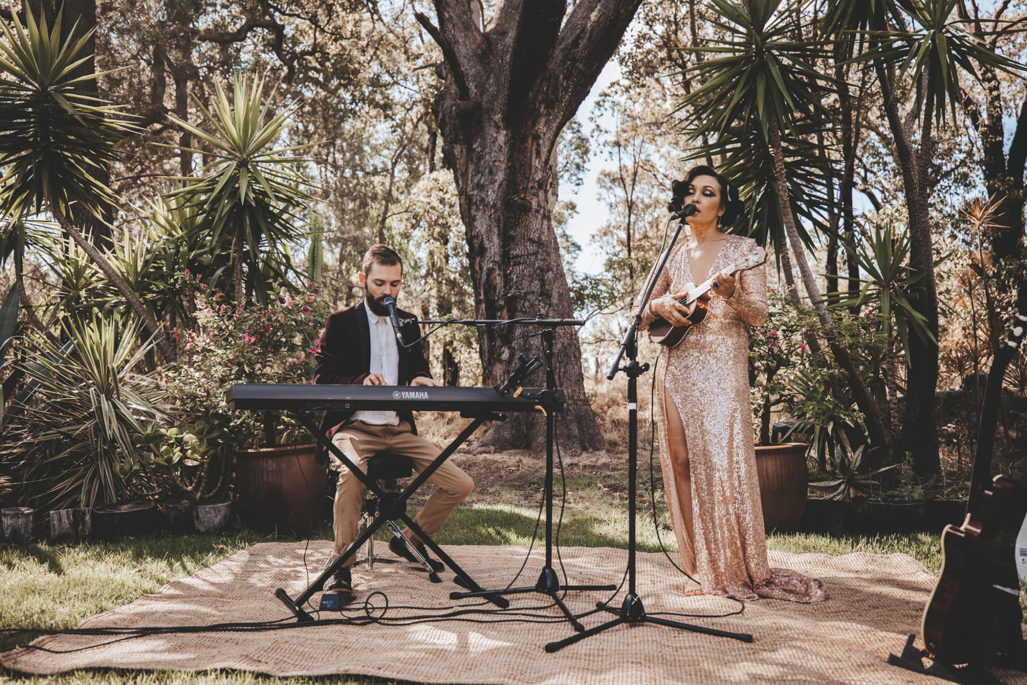 Acoustic duo performing keyboard and ukulele at an outdoor garden wedding ceremony.